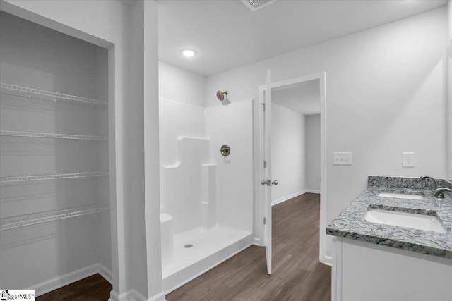 bathroom with hardwood / wood-style flooring, walk in shower, and vanity