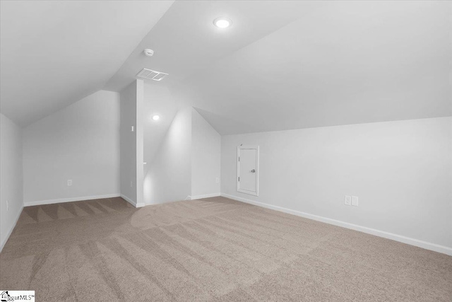 bonus room with lofted ceiling and light colored carpet