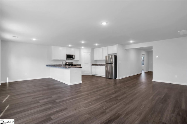 kitchen featuring white cabinetry, kitchen peninsula, stainless steel appliances, dark wood-type flooring, and sink