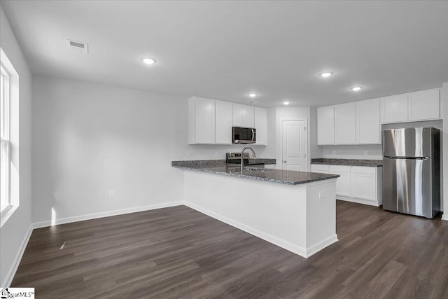 kitchen with white cabinets, dark wood-type flooring, stainless steel appliances, sink, and kitchen peninsula