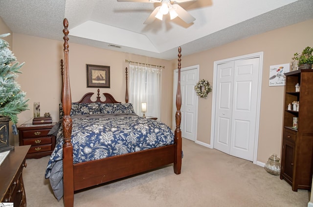 carpeted bedroom with a raised ceiling, ceiling fan, and a textured ceiling