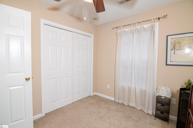 unfurnished bedroom featuring ceiling fan, light carpet, a closet, and a textured ceiling