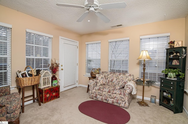 sitting room featuring light carpet, ceiling fan, and a textured ceiling