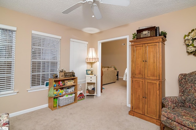 game room featuring ceiling fan, a textured ceiling, and light carpet