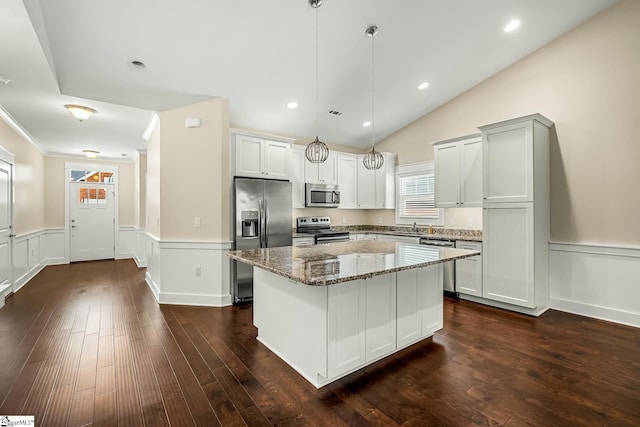 kitchen with dark hardwood / wood-style floors, pendant lighting, a center island, appliances with stainless steel finishes, and stone countertops