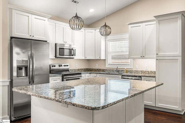 kitchen featuring light stone counters, white cabinetry, a center island, and stainless steel appliances