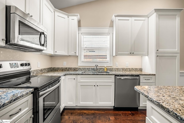 kitchen with sink, white cabinetry, light stone countertops, appliances with stainless steel finishes, and dark wood-type flooring