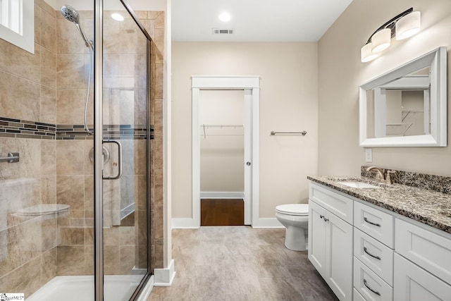 bathroom featuring an enclosed shower, vanity, and toilet