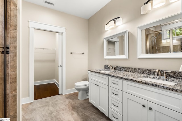 bathroom with toilet, vanity, and a tile shower