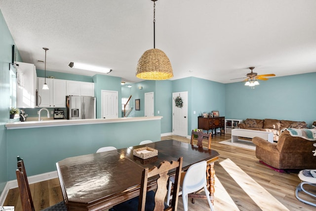 dining room with ceiling fan, sink, and light hardwood / wood-style flooring