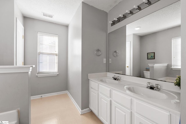 bathroom with toilet, vanity, and a textured ceiling