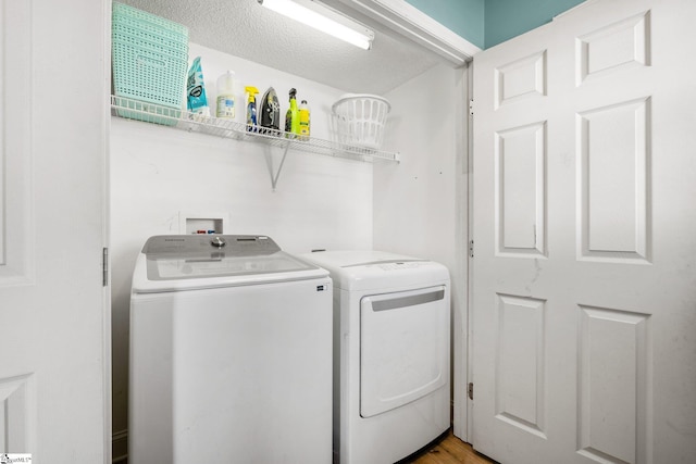 laundry room with a textured ceiling and separate washer and dryer