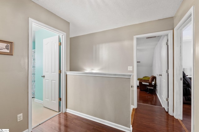 corridor with a textured ceiling and dark hardwood / wood-style floors