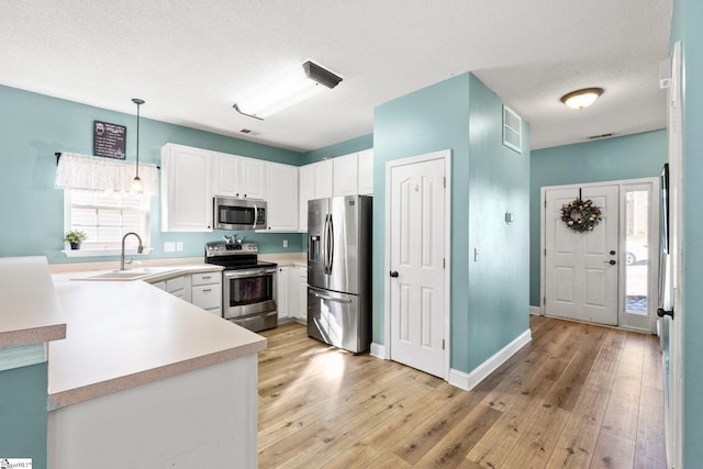 kitchen featuring white cabinetry, sink, pendant lighting, and appliances with stainless steel finishes