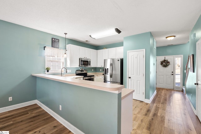 kitchen with white cabinets, stainless steel appliances, a healthy amount of sunlight, hanging light fixtures, and kitchen peninsula