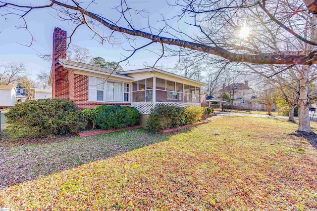 view of side of home with a yard and a sunroom