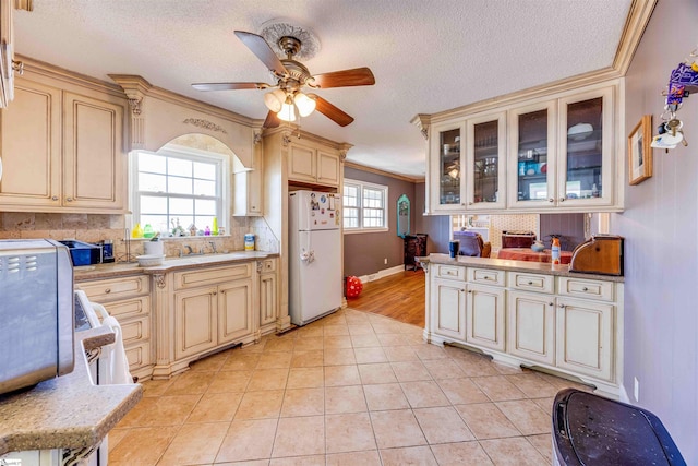 kitchen featuring cream cabinetry, crown molding, and white fridge