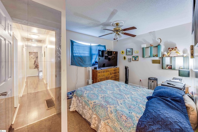 carpeted bedroom with ceiling fan and a textured ceiling