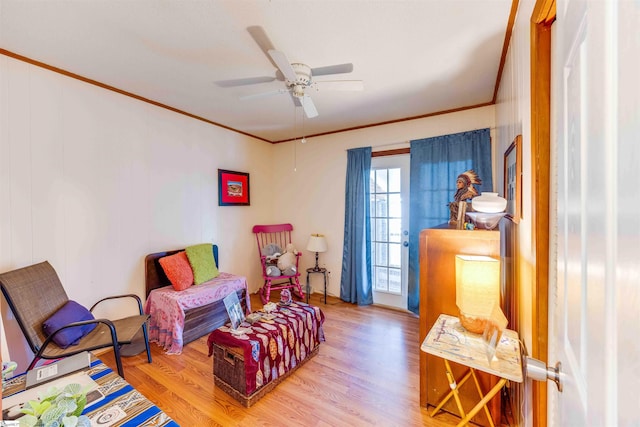 sitting room featuring ceiling fan, ornamental molding, and wood-type flooring