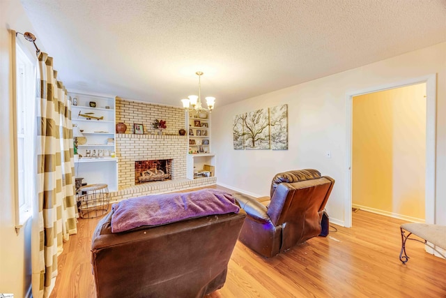 bedroom with a textured ceiling, a chandelier, a fireplace, and light hardwood / wood-style flooring