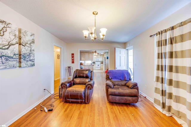 living area featuring ceiling fan with notable chandelier, wood-type flooring, and a textured ceiling