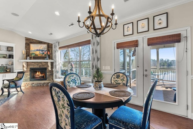 dining area with hardwood / wood-style flooring, a stone fireplace, lofted ceiling, french doors, and a water view