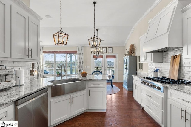 kitchen with premium range hood, white cabinetry, appliances with stainless steel finishes, hanging light fixtures, and sink