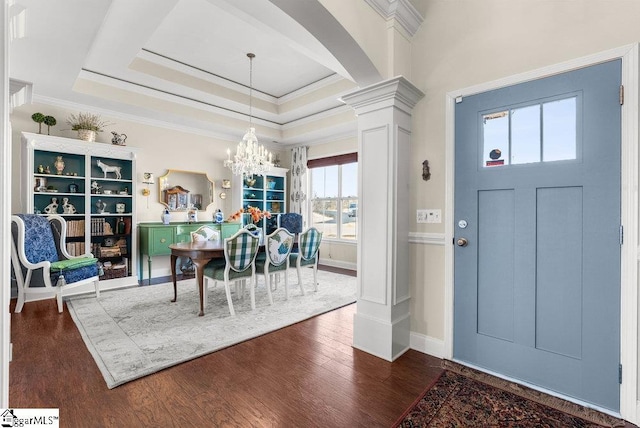 dining space with an inviting chandelier, ornate columns, dark hardwood / wood-style floors, a tray ceiling, and ornamental molding