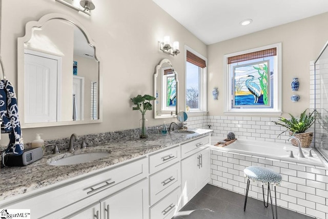 bathroom featuring tiled tub, vanity, and tile patterned flooring