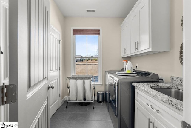 washroom with cabinets, washing machine and clothes dryer, and sink