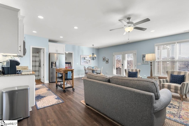 living room with ceiling fan with notable chandelier and dark wood-type flooring