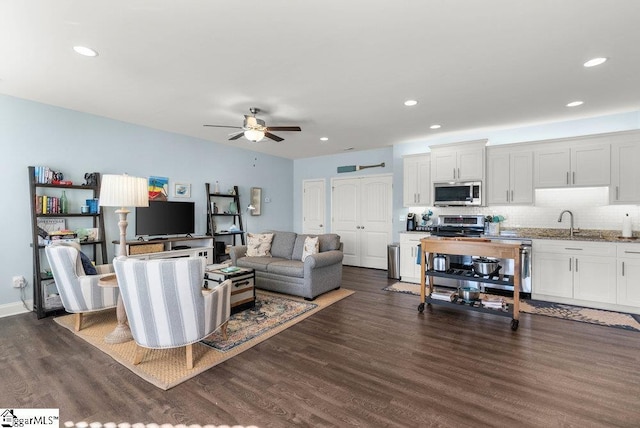 living room featuring ceiling fan, dark hardwood / wood-style flooring, and sink