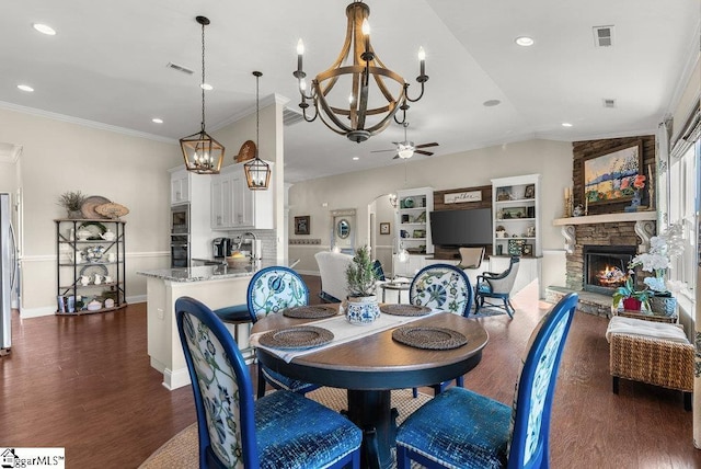 dining area featuring dark hardwood / wood-style floors, lofted ceiling, a fireplace, ornamental molding, and ceiling fan with notable chandelier