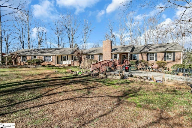 rear view of property with brick siding, a yard, and a chimney