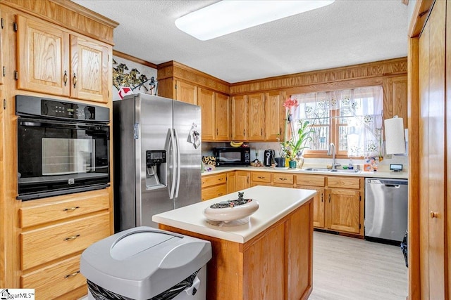 kitchen featuring a textured ceiling, a sink, a kitchen island, light countertops, and black appliances