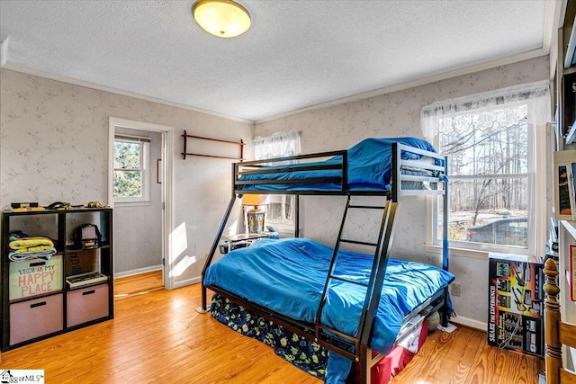 bedroom with a textured ceiling, crown molding, and light wood-type flooring