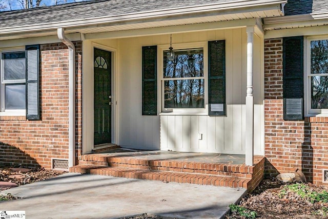 doorway to property featuring brick siding, crawl space, a shingled roof, and board and batten siding