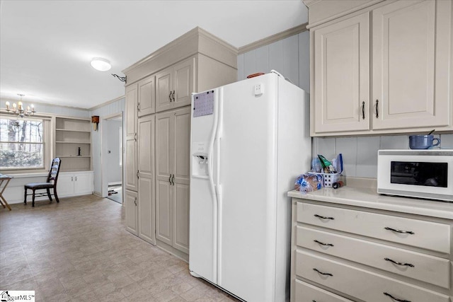 kitchen featuring light floors, light countertops, ornamental molding, a chandelier, and white appliances