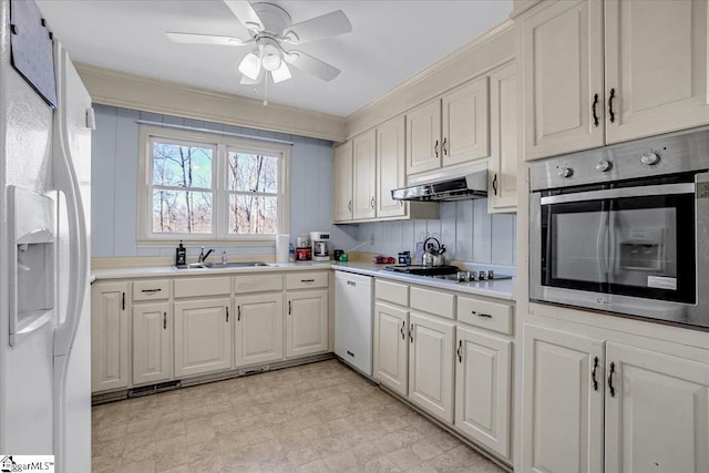 kitchen featuring ceiling fan, sink, crown molding, white appliances, and white cabinetry