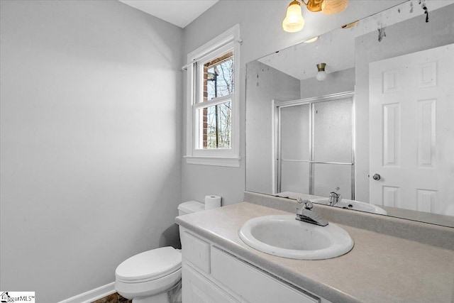 full bathroom with a stall shower, vanity, toilet, and baseboards