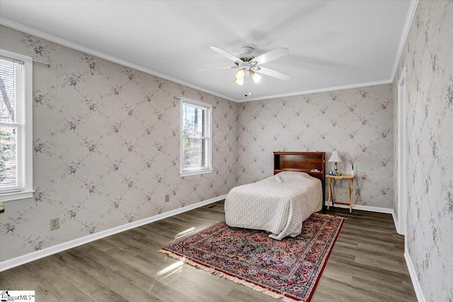 bedroom featuring baseboards, ornamental molding, wood finished floors, and wallpapered walls