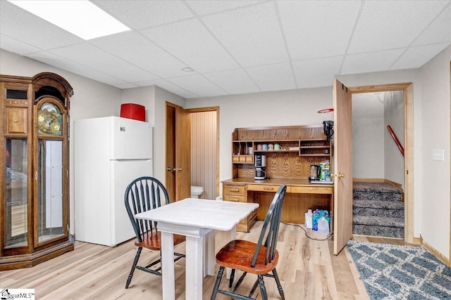 dining area featuring a paneled ceiling and light hardwood / wood-style flooring