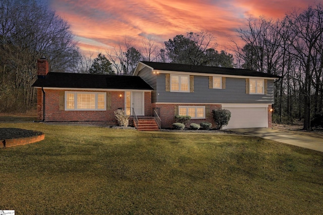 tri-level home with a garage and a lawn