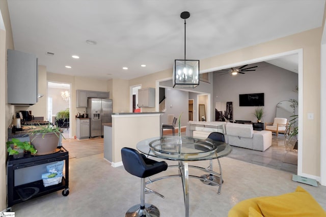 carpeted dining room featuring vaulted ceiling and ceiling fan with notable chandelier