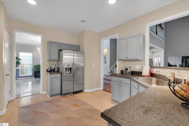 kitchen featuring light tile patterned floors, stainless steel refrigerator with ice dispenser, sink, and gray cabinets