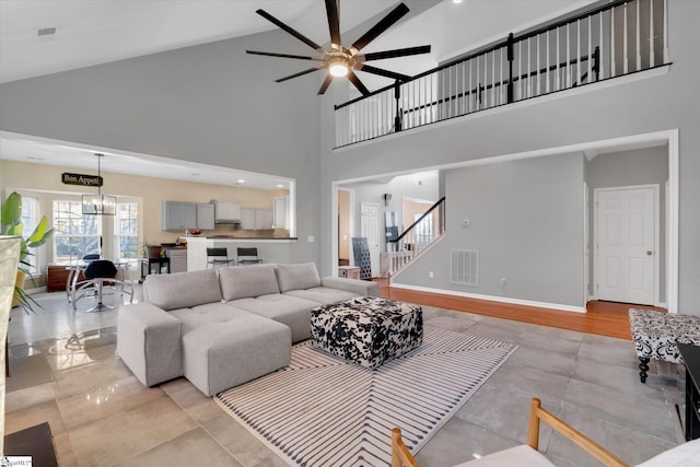 living room featuring high vaulted ceiling and ceiling fan with notable chandelier