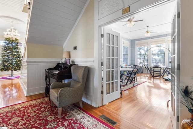 living area with ceiling fan, wood-type flooring, ornamental molding, and lofted ceiling