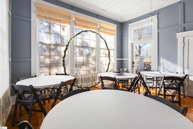 dining room with dark wood-type flooring, ornamental molding, and a healthy amount of sunlight