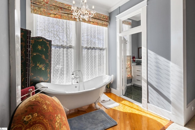 bathroom featuring hardwood / wood-style floors, a tub to relax in, crown molding, and a notable chandelier