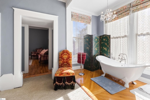 bathroom featuring a chandelier, a washtub, ornamental molding, and hardwood / wood-style flooring